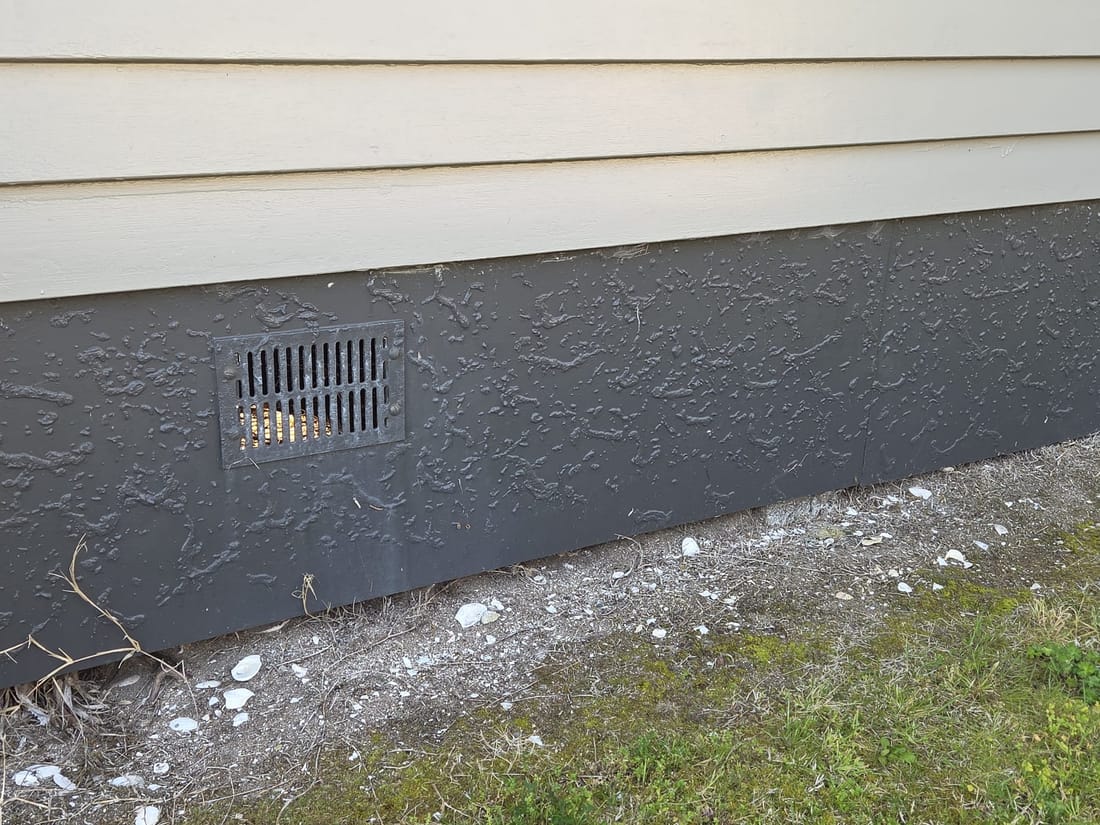 Asbestos-cement subfloor base board with a vent on a typical 1970s New Zealand home