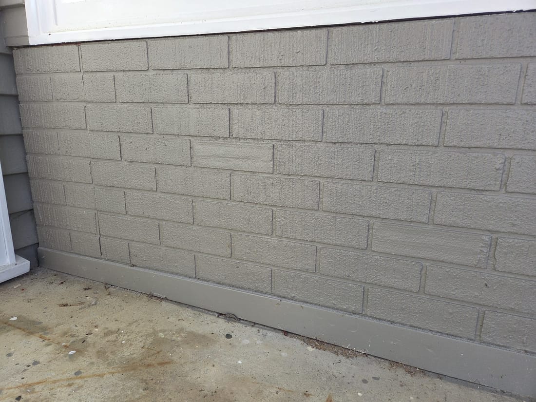 Painted faux brick asbestos-cement cladding panels pressed with a brick-and-mortar pattern on a 1970s NZ home
