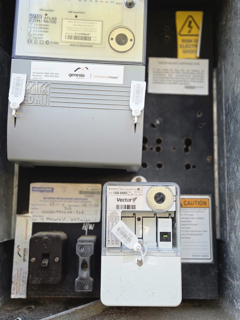 Asbestos-containing mounting board inside an old power meter box, covered in drill holes