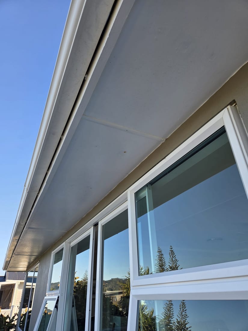 Asbestos-cement soffit lining under the eaves, joined with cover strips and rusted nail fixings